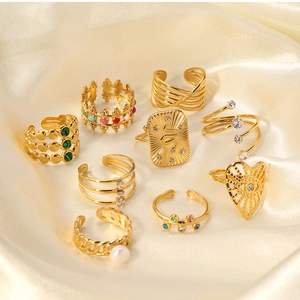 Detailed close-up of vintage gold rings with zircon and enamel on champagne silk fabric