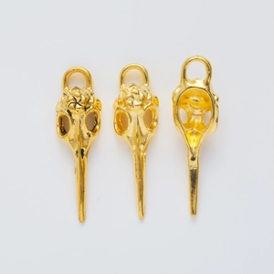 Detailed macro view of three golden DIY bird skull charms with intricate metal texture