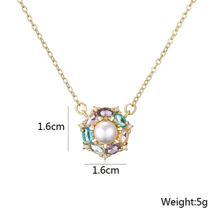 Macro detail of gold-plated flower pendant with pearls, zirconias, and colorful gems