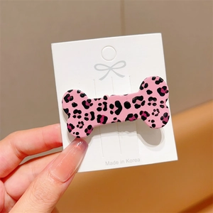 Detailed shot of pink leopard print bone-shaped hair clip on a white card