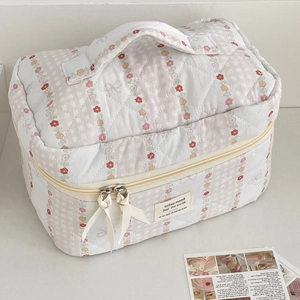 Detailed close-up of quilted floral makeup bag with ribbon zipper and handle