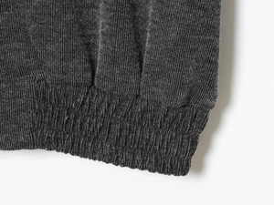 Detail of ribbed knit fabric texture and elastic cuff on a charcoal grey tracksuit