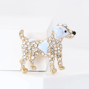 Macro detail of dog brooch with clear crystals and light blue enamel on gold base