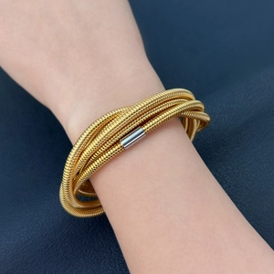 Close-up of golden multi-layer spring cuff bracelet on wrist with snake chain texture