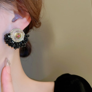 Detailed close-up of retro floral stud earring with black beads and red zircon accent