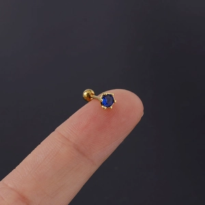 Detail of 20G gold-plated stainless steel stud earring with a royal blue zircon on fingertip