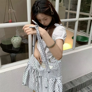 Detail of checkered tote bag with black bow accents and adjustable tie shoulder strap