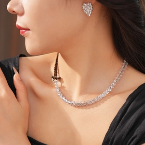 Close-up of heart-shaped zircon earrings and tiger eye necklace set on model