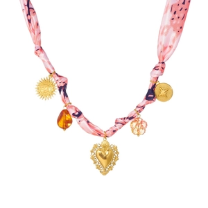 Collier foulard en soie rose noué avec pendentifs soleil et cœur dorés sur fond blanc
