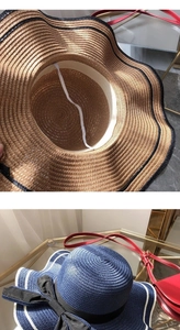 Detail of a wavy brim straw sun hat with decorative bow and secure wind strap