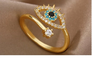 Macro shot of gold evil eye ring with blue stones and crystals on brown silk