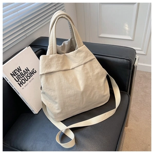 Detail of cream nylon handbag featuring a pleated texture design on a leather chair
