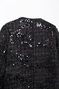 Detaillierte Makroansicht von schwarzem Tweedstoff mit schimmernden Pailletten und Textur