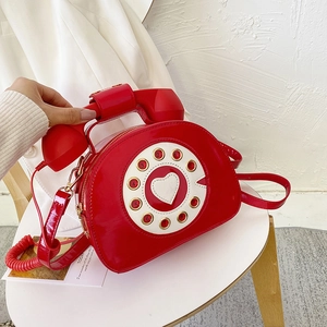 Detail of red patent leather creative telephone-shaped shoulder bag with dial and heart design