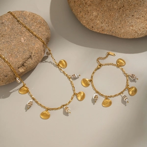 Ensemble collier et bracelet avec pendentifs coquillages dorés sur galets de plage