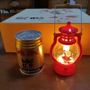 Mini red Christmas lantern with glowing Santa Claus figure next to a 250ml soda can