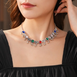 Close-up of vintage silver necklace with colorful gemstones and tassel details on model