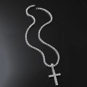 Silver tennis chain necklace with iced out cross pendant on reflective black surface