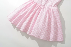 Detailed view of pink plaid dress featuring white buttons and a soft cotton texture