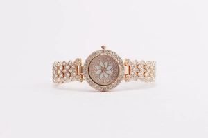 Macro shot of rose gold flower watch featuring crystal bezel and white floral dial detail