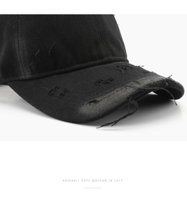 Detailed close-up of distressed cotton twill fabric with ripped edges on a black baseball cap