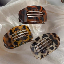Detailed view of tortoiseshell claw clips in dark brown and beige on silk fabric