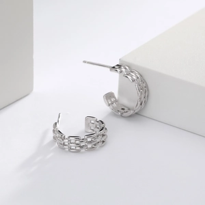 Detail view of silver braided twist geometric hoop earrings with polished metallic texture