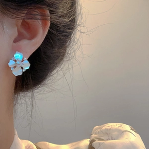 Elegant floral stud earrings with white mother-of-pearl petals and cubic zirconia on model