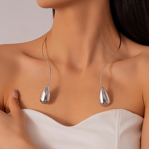 Détail du collier ras du cou argenté en forme de goutte au design métal épuré