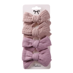 Close-up of four-piece linen bow hair clip set in dusty pink and lilac purple colors