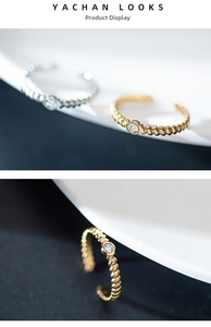 Detail of twisted metal adjustable rings with round zircon inlay in gold and silver