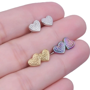 Close-up of heart-shaped stainless steel earrings in silver, gold, and rainbow colors