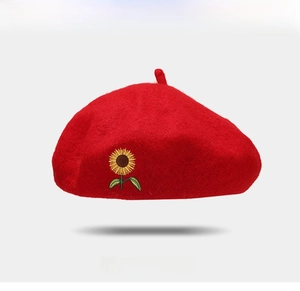 Close-up of red wool beret featuring detailed sunflower embroidery and soft fabric texture
