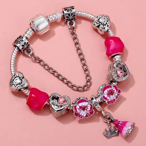 Silver snake chain bracelet with pink glass beads and crown charms on pink background