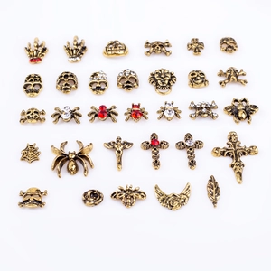 Macro view of vintage gold gothic nail charms with skull, spider, and cross designs