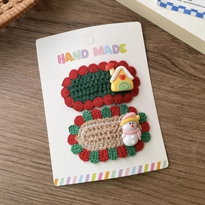 Detailsicht handgefertigter gestrickter Haarspangen mit Schneemann und Häuschen-Motiven
