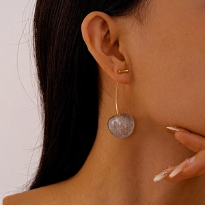 Close-up of clear acrylic cherry earrings with silver glitter and gold hooks on a model