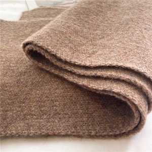 Macro shot of brown knitted scarf fabric showing soft wool texture and thick fiber details