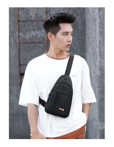 Close-up of black tactical oxford chest bag with front zipper pocket and logo on male model