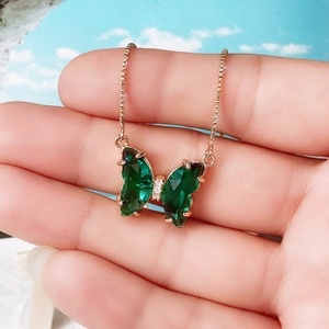 Macro shot of rose gold butterfly pendant necklace with deep green faceted crystals