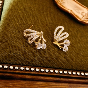Detailed macro view of golden butterfly wing earrings with white zircon pavé setting