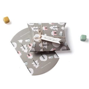 Detail view of mini grey pillow gift boxes with twine, tags, and stylized house patterns