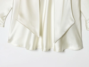 Detail of white satin dress showing high-quality hem stitching and silky fabric texture