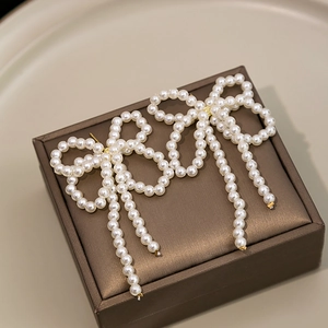 Macro shot of long tassel pearl earrings with bow knot design on a jewelry box