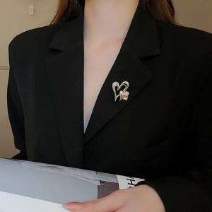 Close-up of a double heart gold brooch with sparkling rhinestones on a black suit lapel