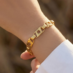 Chic bracelet trèfle en acier inoxydable plaqué or 18 carats porté au poignet au soleil