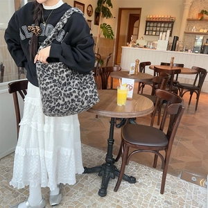 Faux shearling leopard print tote bag styled with a white lace skirt in a cafe setting