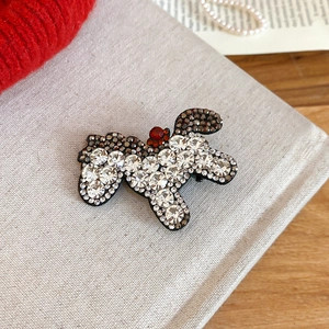 Detailed close-up of a dog-shaped hair clip with sparkling white and red rhinestones