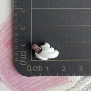 Macro shot of miniature cream dessert charm with Happy sign, size reference 2cm x 1.5cm