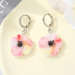 Detailed top view of a delicate floral earring with pink gradient petals on a tray